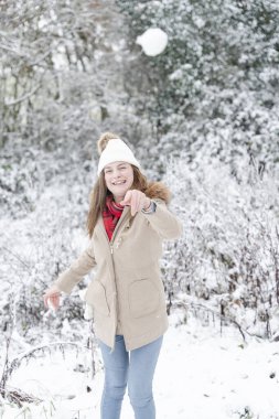 Smiling woman throwing snow ball in winter landscape