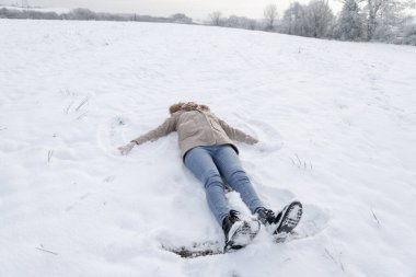 Kış manzarasında kar meleği yapan kadın
