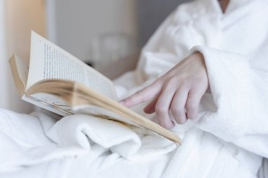 Close-up of woman in bathrobe reading book
