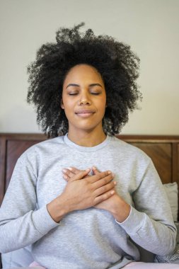 Genç kadın yatakta meditasyon yapıyor.