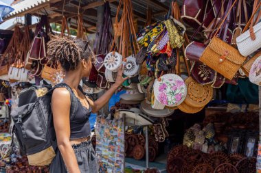 Indonesia, Bali, Female tourist looking at straw bags in traditional market