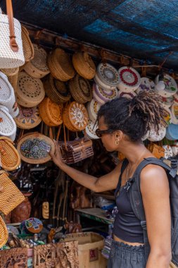 Indonesia, Bali, Female tourist looking at straw bags in traditional market