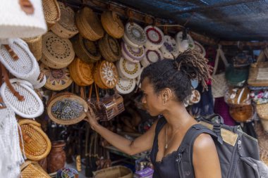 Indonesia, Bali, Female tourist looking at straw bags in traditional market