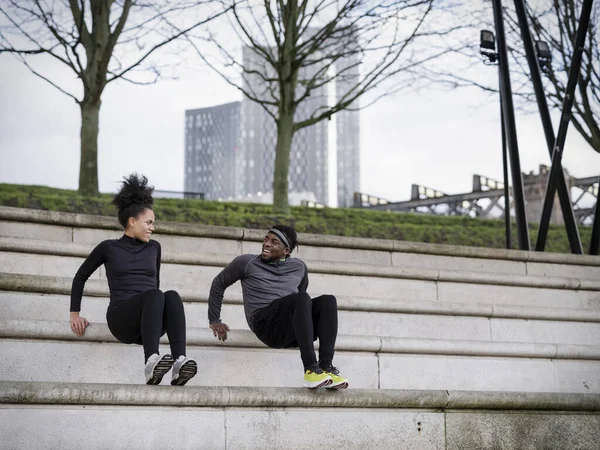 Athletic man and woman exercising on steps outdoors