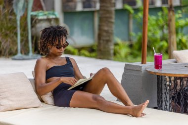 Woman in swimsuit and sunglasses reading