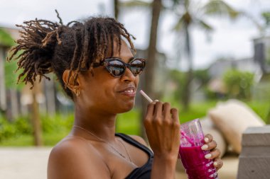 Smiling woman enjoying smoothie on terrace