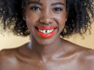 Kıvırcık saçlı, gülümseyen kadının stüdyo portresi.