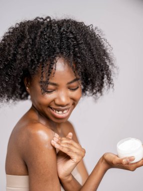 Koluna nemlendirici sürerken gülümseyen kadının stüdyo portresi