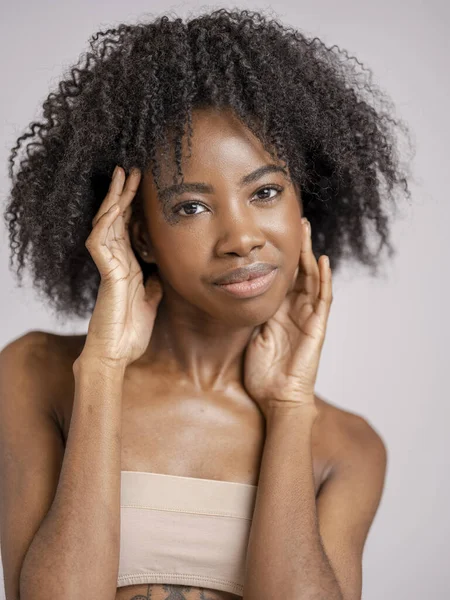 Kıvırcık saçlı, gülümseyen kadının stüdyo portresi.