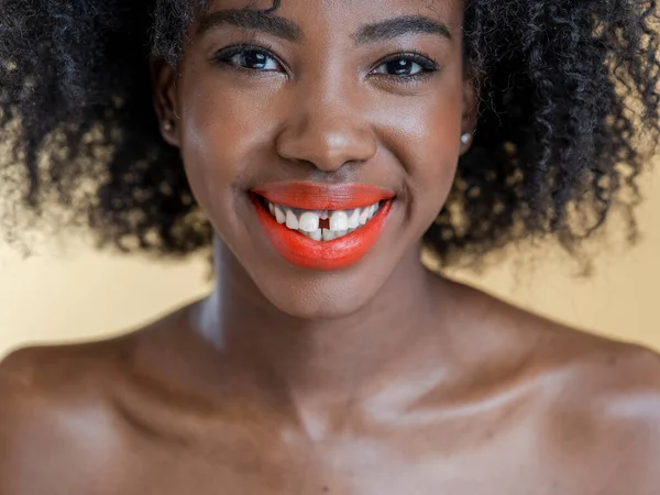 Kıvırcık saçlı, gülümseyen kadının stüdyo portresi.