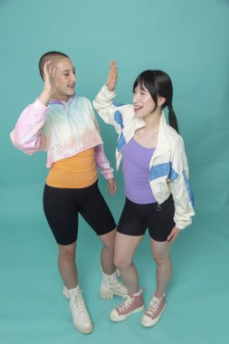 İki gülümseyen kızın beşlik çakışının stüdyo çekimi.