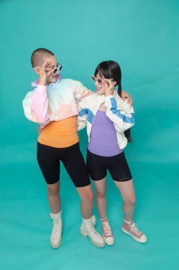 Güneş gözlüğü takan gülümseyen iki kızın stüdyo portresi