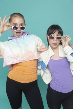 Stüdyo portresi. Güneş gözlüğü takan ve surat yapan iki kız.