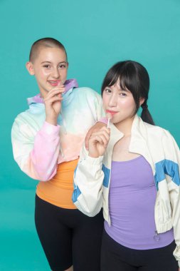 Lolipoplu iki gülümseyen kızın stüdyo portresi.