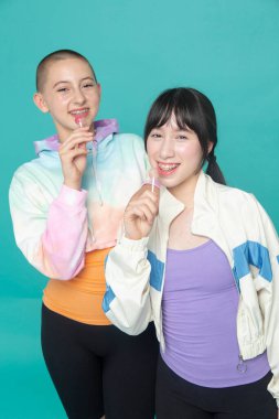 Lolipoplu iki gülümseyen kızın stüdyo portresi.