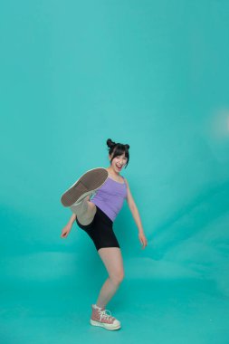 Tek ayak üzerinde duran gülümseyen kızın stüdyo portresi.