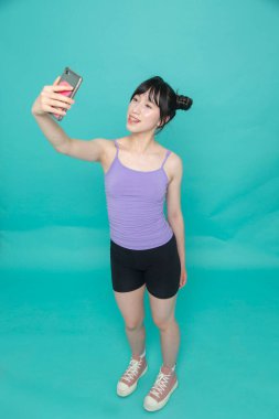 Stüdyo çekiminde gülümseyen kız selfie çekiyor.