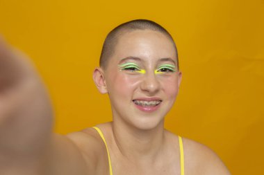 Neon renkli makyajlı gülümseyen kızın stüdyo portresi.