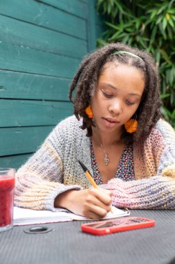 Bahçede günlük tutan genç bir kadın.