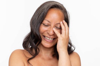 Studio portrait of smiling shirtless woman with eyes closed touching face
