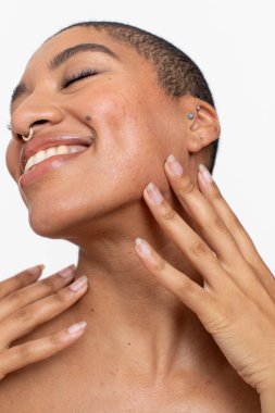 Studio portrait of smiling woman with eyes close touching face