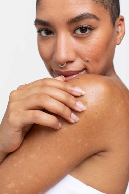 Burun halkalı gülümseyen bir kadının stüdyo portresi.