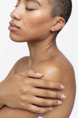 Studio shot of shirtless woman with arms crossed and eyes closed
