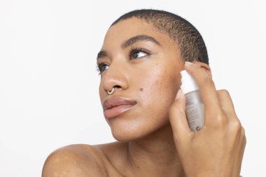 Studio portrait of woman applying face serum