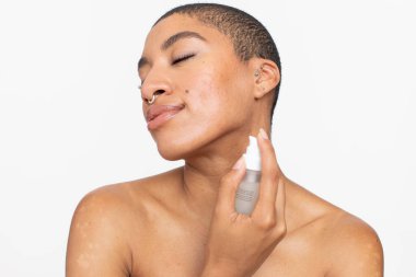 Studio portrait of smiling woman applying face serum
