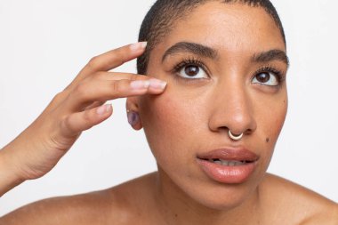 Studio portrait of woman with nose ring touching face