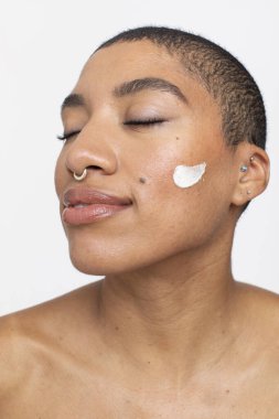 Studio portrait of woman with face cream on cheek