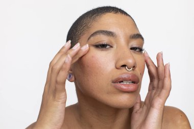 Studio portrait of woman with nose ring touching face
