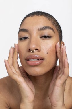 Studio portrait of woman with nose ring touching face