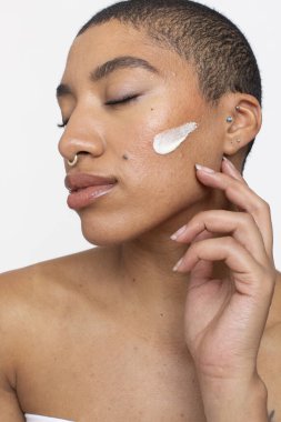 Studio portrait of woman face cream on cheek