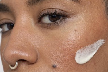 Close-up of woman face cream on cheek