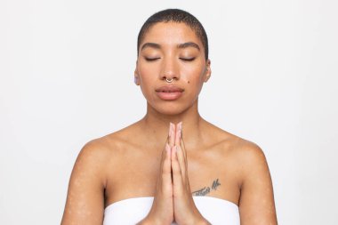 Studio portrait of woman meditating with eyes closed and hands clasped