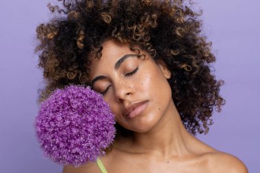 Portrait of woman with closed eyes holding purple flower