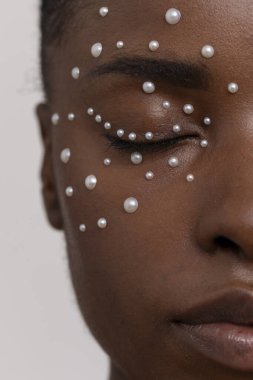 Gözleri kapalı, inci çilli genç bir kadın.