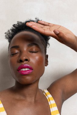 Woman with closed eyes shielding face with hand