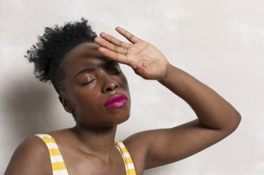 Woman with closed eyes shielding face with hand