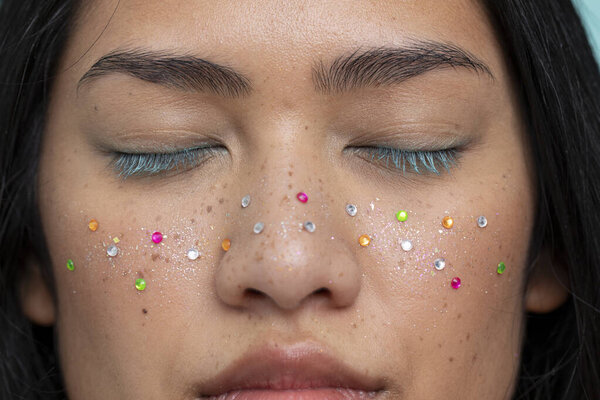Portrait of woman with closed eyes with colorful shiny freckles