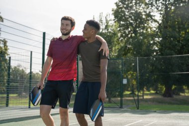 Pickleball sahasında gülümseyen adamlar