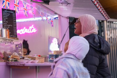 Türbanlı genç bayan turistler çörek alıyor.