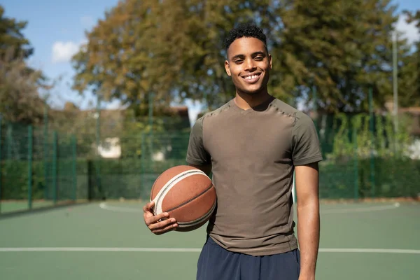 Basketbol sahasında gülümseyen bir adamın portresi.