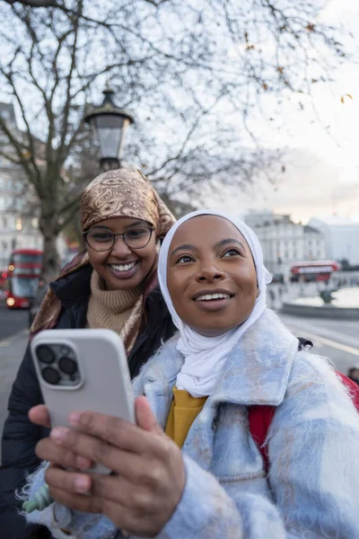 İngiltere, Londra ve Trafalgar Meydanı 'nda telefon kullanan tesettürlü genç bayan turistler