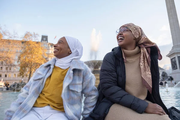 İngiltere, Londra ve genç kadın turistler şehir meydanında dinleniyor