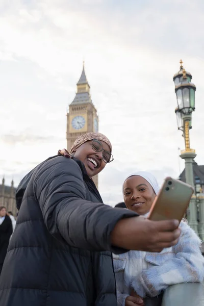 İngiltere, Londra ve genç kadın turistler Westminster Köprüsü 'nde selfie çekiyorlar.