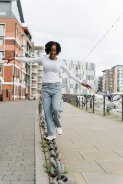 Gülümseyen kadın şehirde zincir halkası üzerinde dengede duruyor.