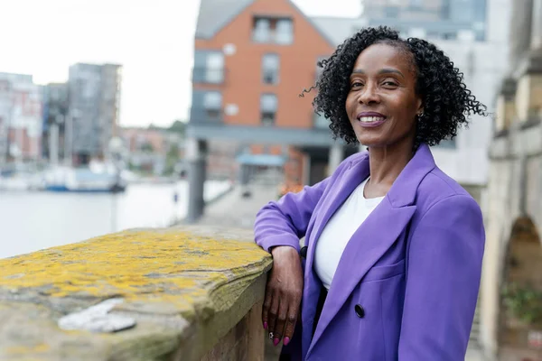 Portrait of smiling woman standing by riverbank