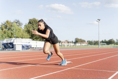 Stadyumdaki başlangıç çizgisinde koşan bayan sporcu
